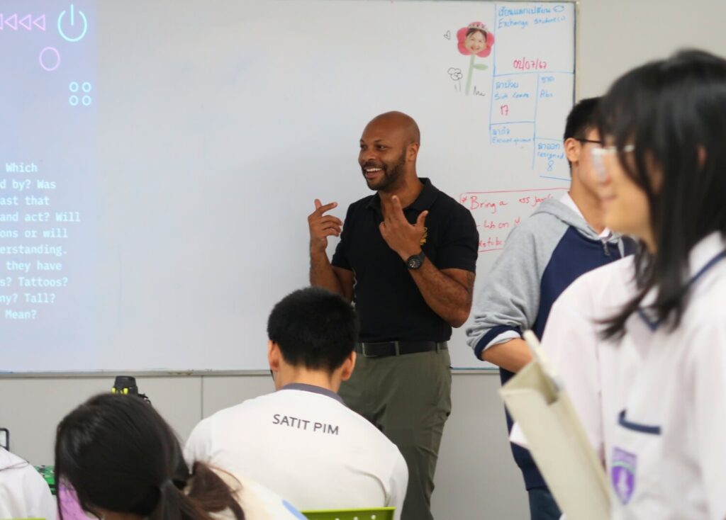Teacher Vic smiling while leading an interactive English lesson at a Thai secondary school with the SPIM BFITS Program