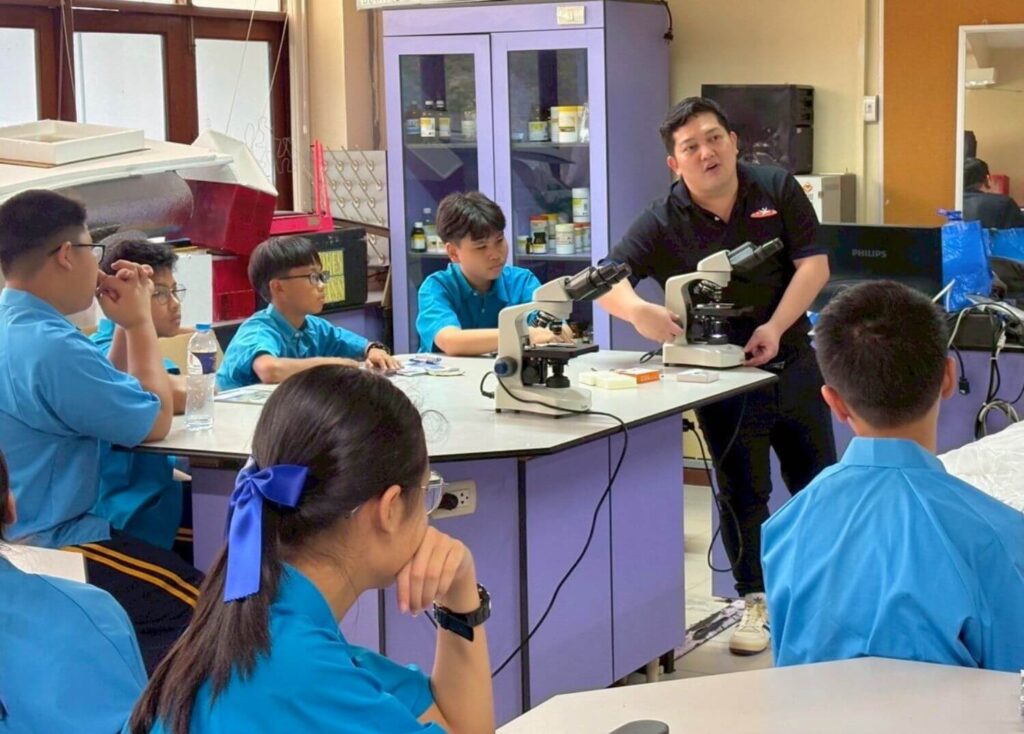 BFITS Teacher Anthony Ferrer guiding students through microscope use during a Preparatory Course Science laboratory activity